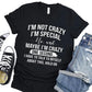 Black t-shirt with humorous text design on a wooden surface with shoes and jeans.